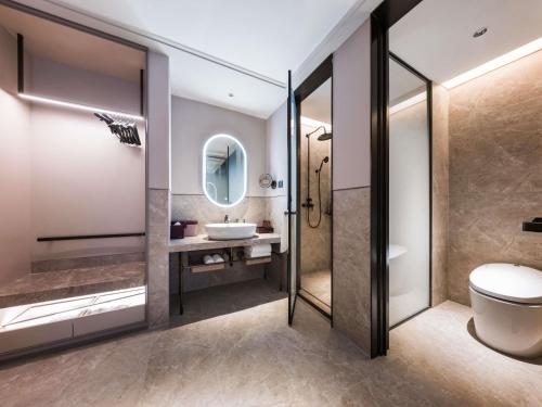 a bathroom with a toilet and a sink and a mirror at Mercure Xi'an New Software City in Xi'an