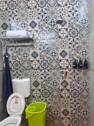 a bathroom with a toilet and a tile wall at The Doghouse in Dehradun
