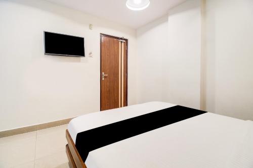 a white room with a bed and a television at OYO Hotel O Allipuram Near Railway Station in Visakhapatnam