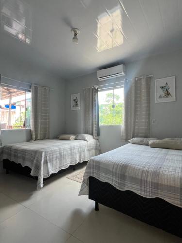 two beds in a room with two windows at Recanto Paraiso Tropical- Praia Ajuruteua in Bragança