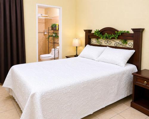a bedroom with a large white bed and a bathroom at Casa cómoda en zona residencial Ideal para familias y grupos in Villa Nueva