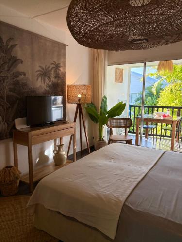a bedroom with a bed and a television and a balcony at Studio Atoumo Marine 5 in Saint-François