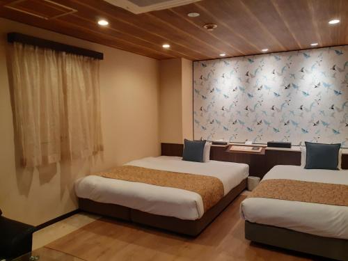 two beds in a hotel room with a wall mural at Hotel Moana Otsuka (Adult Only) in Tokyo