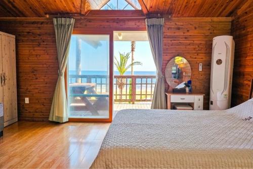 a bedroom with a bed and a view of the ocean at Long Beach Pension in Seogwipo