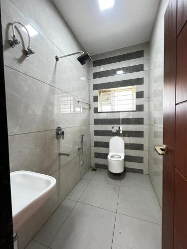 a bathroom with a white toilet and a sink at S Hotel Neela in Musiri