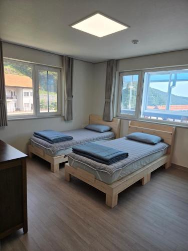 two beds in a room with windows at Herkules Namhae German Village in Namhae