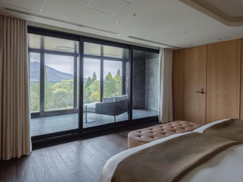 a bedroom with a bed and a large window at Lomä Central Peaks in Shinano