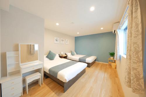 a bedroom with two beds and a flat screen tv at 愉楽の宿 一棟貸切Villa in Osaka