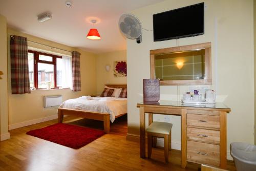 a bedroom with a bed and a desk with a television at The Black Horse Inn in Maidstone