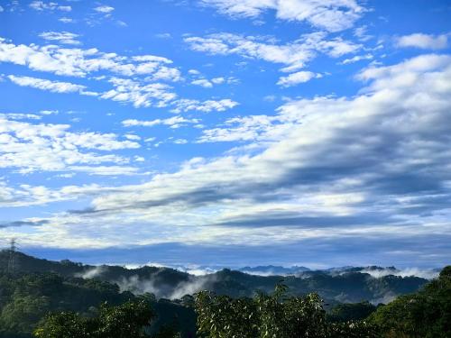 a blue sky with clouds over a mountain range at Fong Chou Chalet in Sanyi