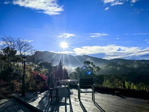 a table and chairs on a deck with a view of the mountains at Fong Chou Chalet in Sanyi