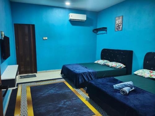 a room with two beds and a blue wall at D'Biru Guest Room in Melur