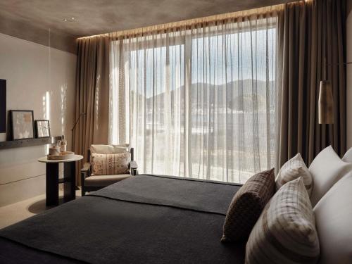 a bedroom with a bed and a large window at Nirema Hotel & Spa Samos - MGallery Collection in Samos