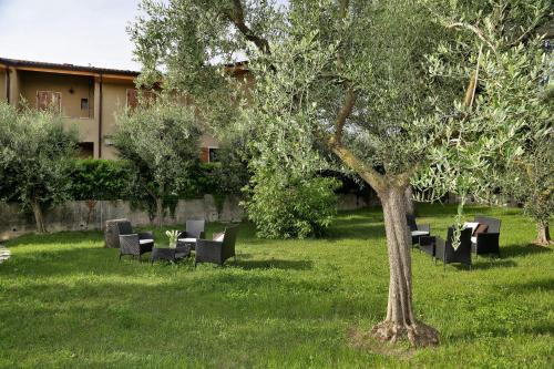 a park with tables and chairs and a tree at Rooms ai Poggi in Bardolino