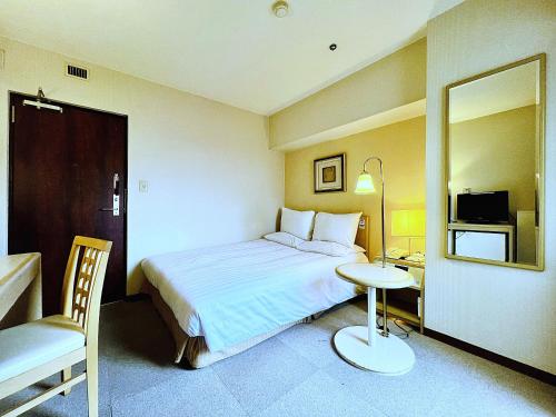 a bedroom with a bed and a table and a mirror at Hotel The Centre Utsunomiya in Utsunomiya