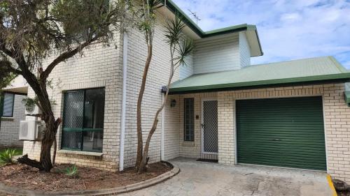 a white brick house with a green garage at The Goose Ponds in North Mackay