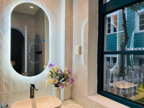 a bathroom with a vase of flowers next to a mirror at KB Villas 51 in Bình Tú