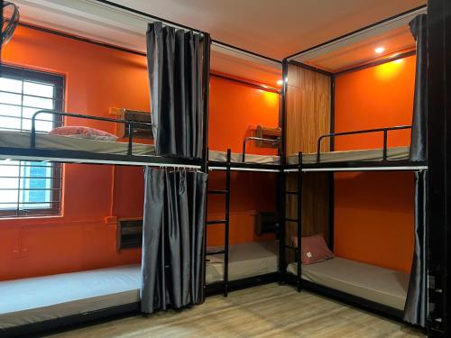 three bunk beds in a room with an orange wall at Ha Giang SkyPath Hostel & Tours in Làng Lap