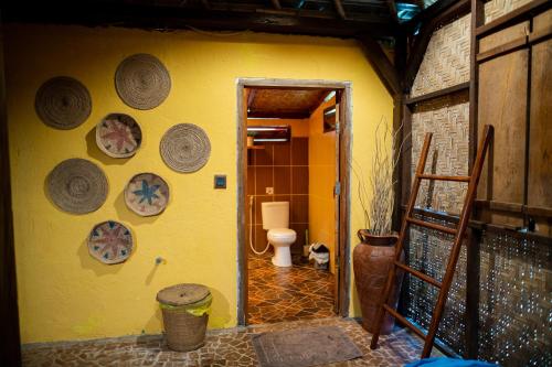 a bathroom with a toilet and a yellow wall at Rinjani Lighthouse in Senaru
