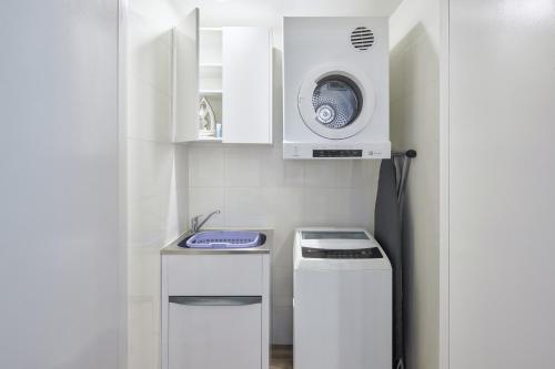 a small kitchen with a microwave and a washing machine at Meriton Suites Mascot Central in Sydney