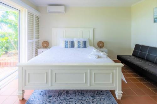 a white bed in a room with a couch at The Sunset Sea in Eimeo