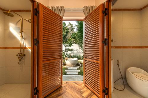 a bathroom with a door open to a tub at The Jam Boutique Hotel in Luang Prabang