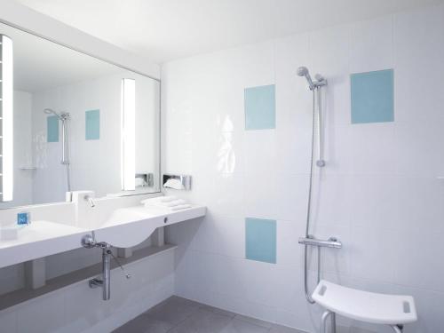 Ein weißes Badezimmer mit zwei Waschbecken und einer Dusche in der Unterkunft Novotel Amboise in Amboise