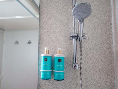 two bottles ofodorizers are sitting on a bathroom wall at Novotel Poissy Orgeval in Orgeval
