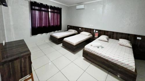 a bedroom with two beds and a window at Hotel Divisa poá in Poá