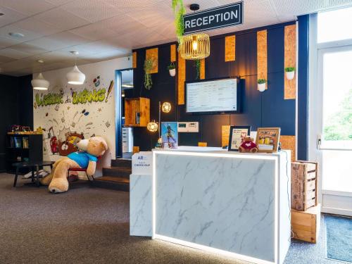 a waiting room with a teddy bear sitting in a chair at Novotel Mulhouse Bâle Fribourg in Sausheim