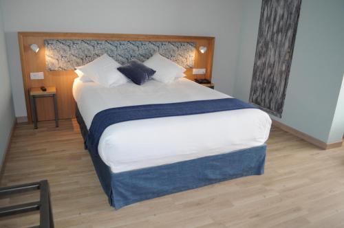 Un dormitorio con una cama grande con sábanas y almohadas blancas. en Hotel Celanova, en Celanova