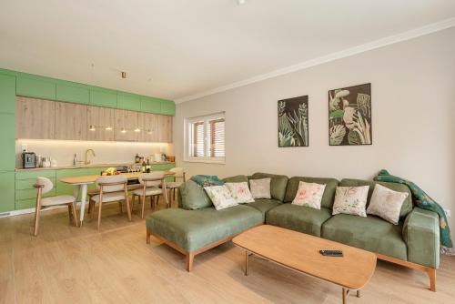 a living room with a green couch and a kitchen at House Olive Tree in Bijela