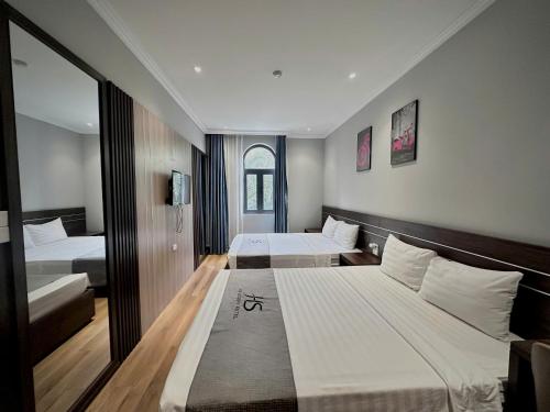 a hotel room with two beds and a mirror at HS Dobry Hotel Ha Long in Ha Long
