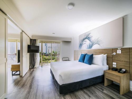 a hotel room with a bed and a tv at Novotel Cairns Oasis Resort in Cairns