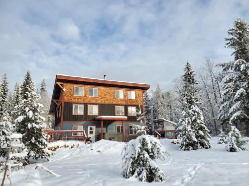 a house in the snow with snow covered trees at GROWL Lodge - Hot Tub & Mountain Views! in Golden