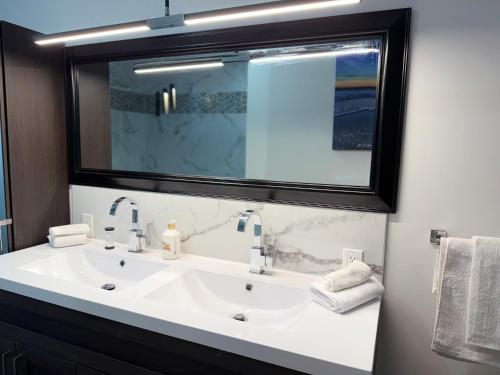 a bathroom with a sink and a large mirror at Manoir Chris in Saint-Augustin-de-Desmaures