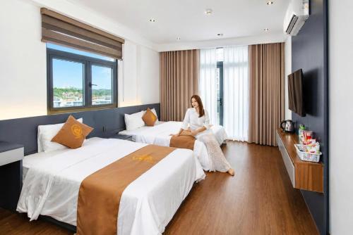 a woman sitting between two beds in a hotel room at The Muse Hotel 1 in Ðố Sơn