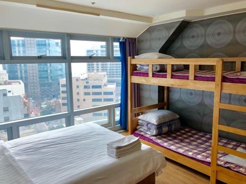 a bedroom with bunk beds and a large window at popcorn hostel haeundae in Ch'ŏngsap'o