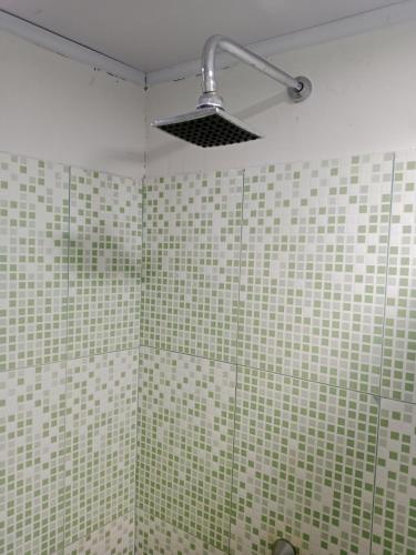 a bathroom with green and white tiled walls and a shower at Hostal Ebenezer Macedonia in Macedonia
