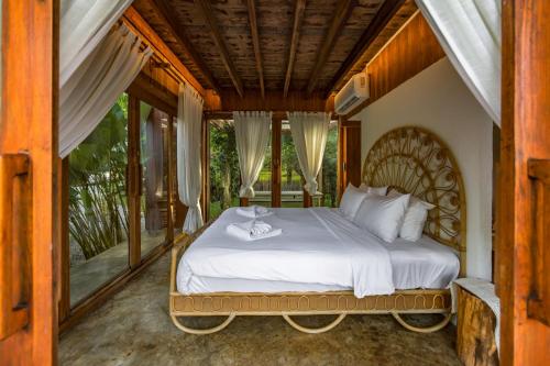 a bedroom with a bed in a room with windows at บ้านนาก๋างโต้ง Baan Na Kang Tong in Ban Kot