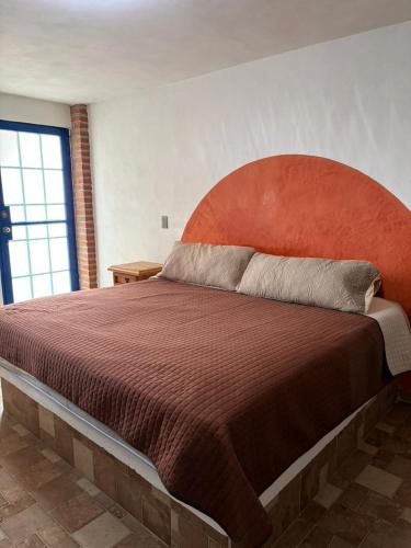 a bedroom with a large bed with an orange headboard at Hotel Casa Don Marcos in Ixtafiayuca