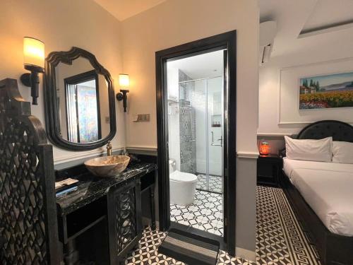 a bathroom with a sink and a bed and a mirror at Dérive Boutique Villa & Apartment Da Nang in Danang