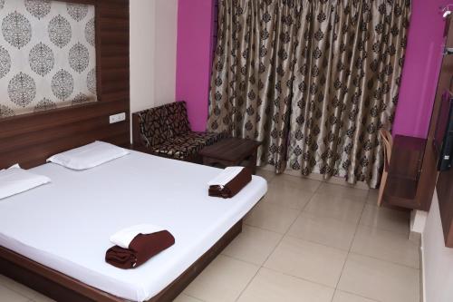 a hotel room with two beds and a chair at Hotel Shoven in Dāvangere