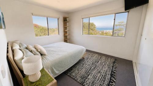 a bedroom with a bed and two windows at SeaSong in Ventnor in Ventnor