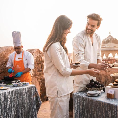 a man and a woman standing next to a table with food at The Leela Palace Jaipur in Jaipur