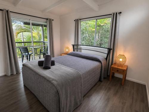 a bedroom with a bed and two windows at Pippies Beachhouse Backpackers in Rainbow Beach
