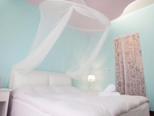 a bedroom with a white bed with a canopy at MINAMI Inn Kenting in Nanwan