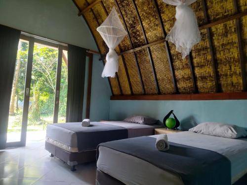 two beds in a bedroom with a roof at Pedidi Penida Hostel in Nusa Penida