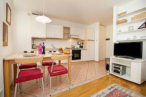 a kitchen with a table and chairs and a television at Appartamento Centro Storico Riva 2 - Happy Rentals in Riva del Garda