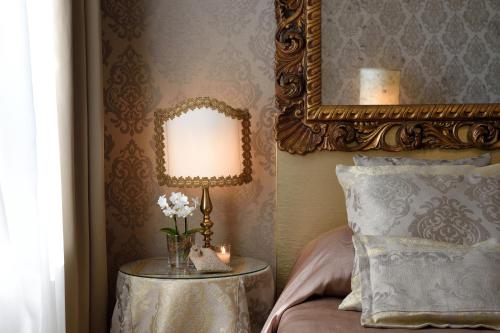 a bedroom with a mirror and a table with a lamp at Hotel Metropole Venezia in Venice